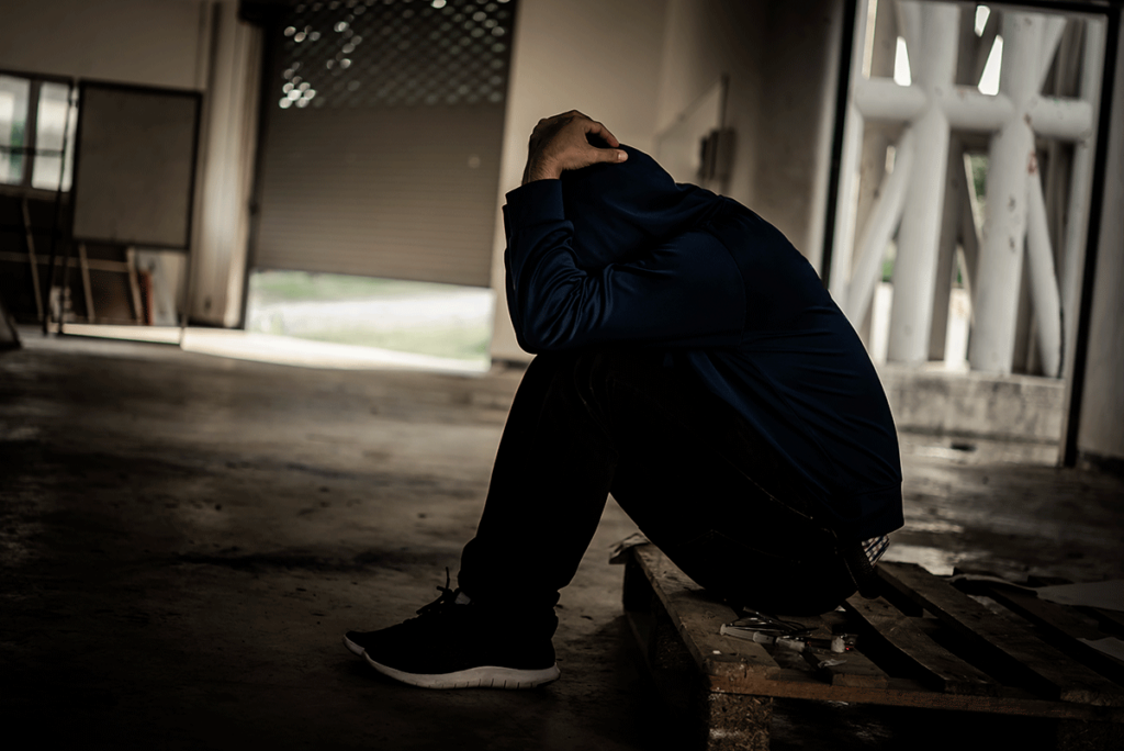 Person hunched over and thinking about the long-term effects of heroin abuse